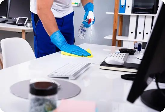A man in blue gloves is wiping down a desk